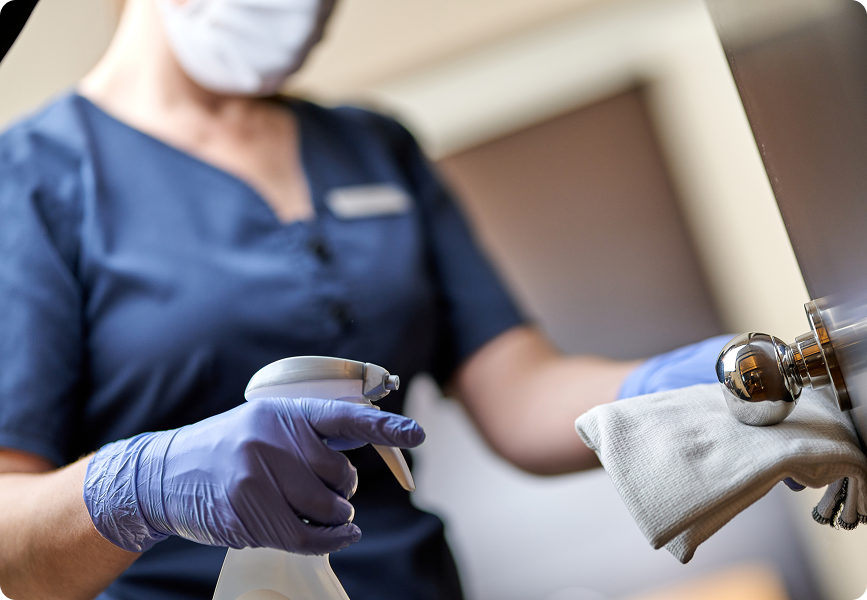 empregada-com-mascara-fazendo-desinfeccao-da-macaneta-da-porta-no-hotel